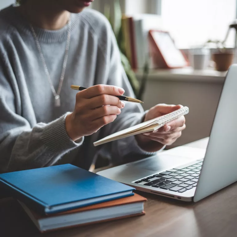 Person mit Notizbuch und Laptop – Darstellung von strukturierter Planung und Online-Coaching.