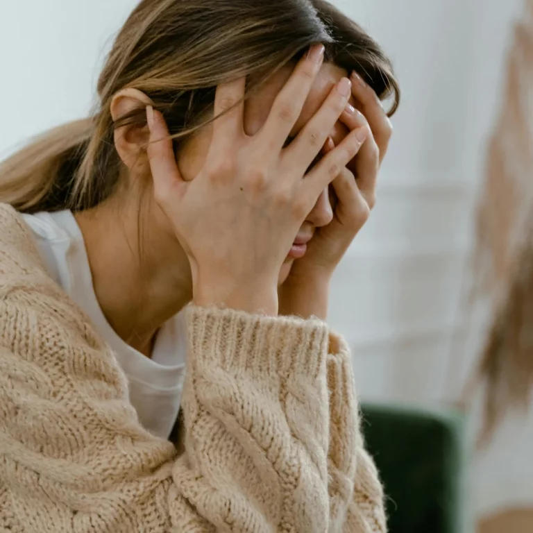 Eine gestresste Frau hält ihren Kopf in den Händen, Symbol für emotionale Belastung und Burnout-Prävention.